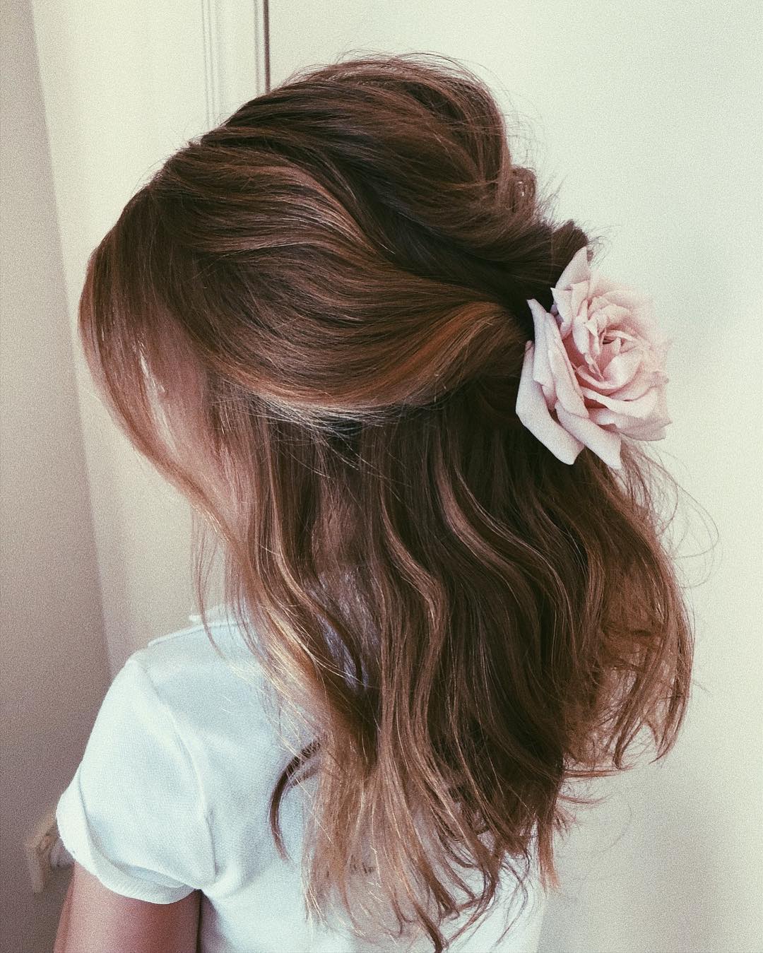 12-volume-with-flowers A voluminous, wavy hairstyle with a single flower tucked behind the ear.