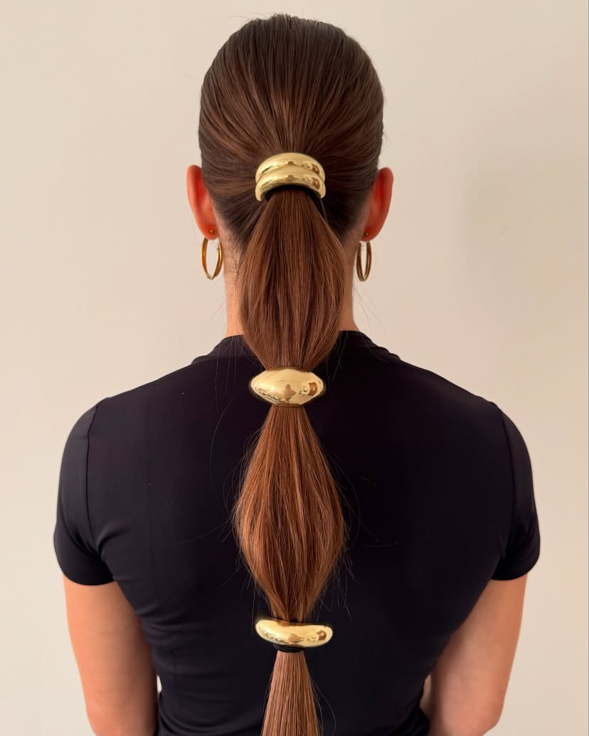 2025-hair-trends-5 Beautiful gold hair cuffs on a low ponytail.