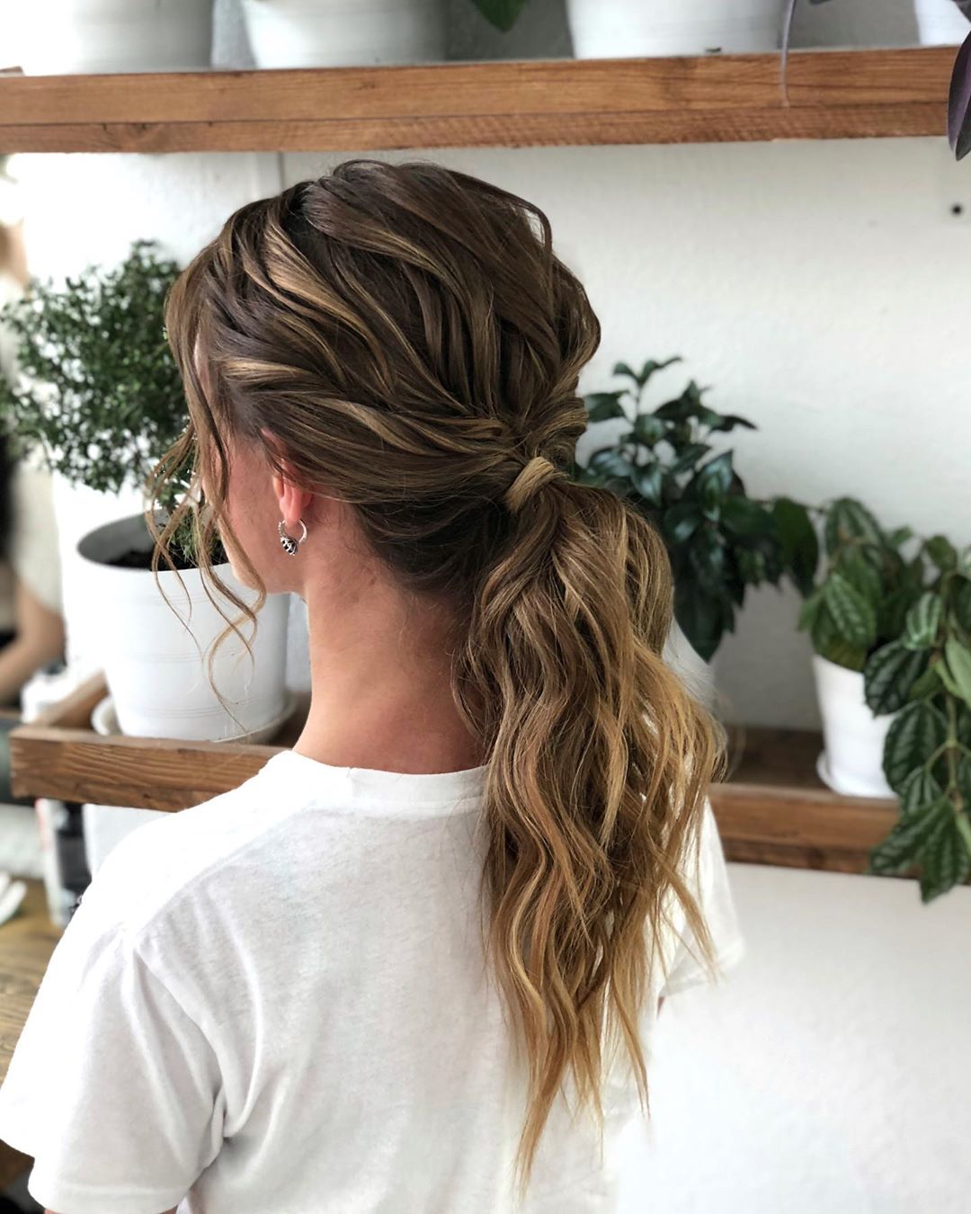 3-wavy-ponytail A low, loose ponytail with soft waves and a piece of hair wrapped around the base.