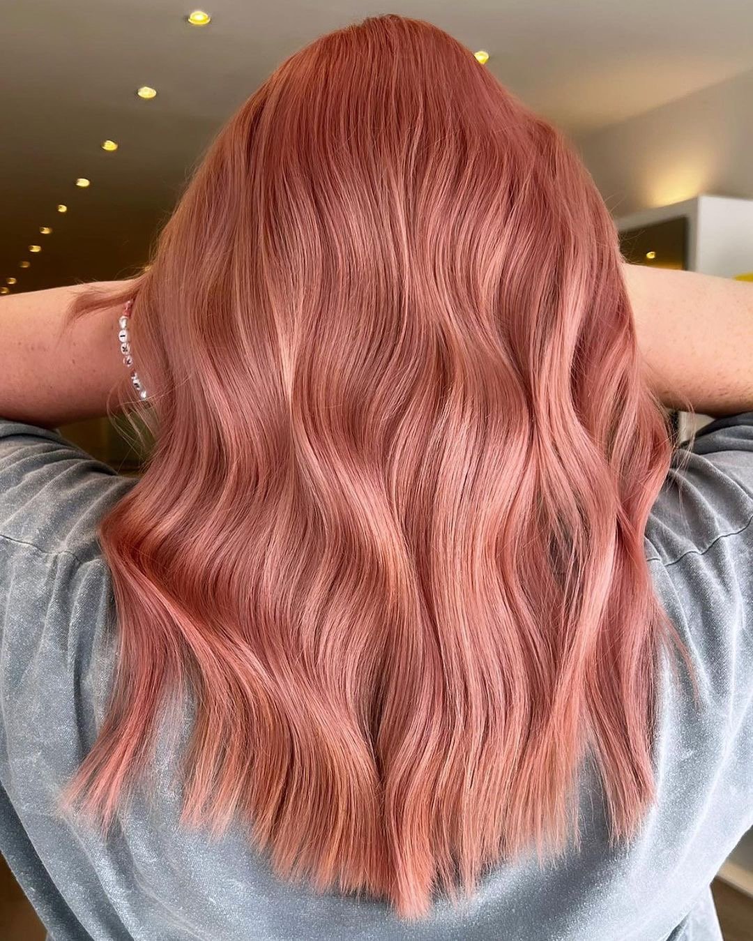 Beautiful rose gold hair color on mid-length wavy hair.