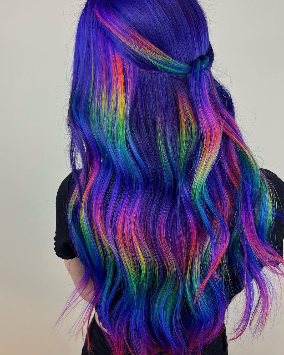 Beautiful purple hair with rainbow highlights on long wavy hair.