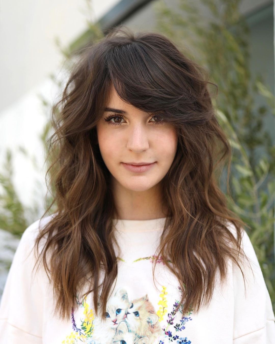 Woman with a side-swept bangs and long layered haircut.
