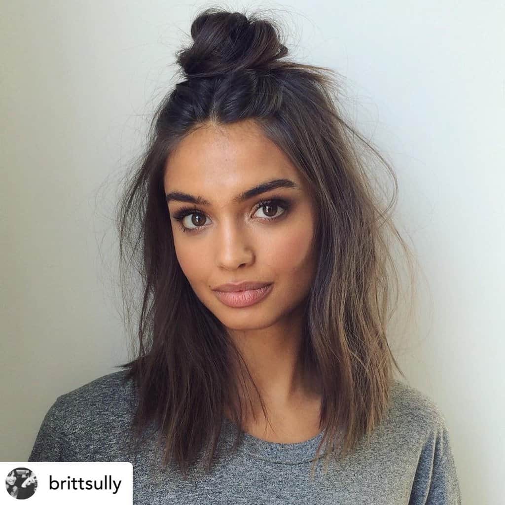 Half-up topknot on beautiful woman with medium-length hair.