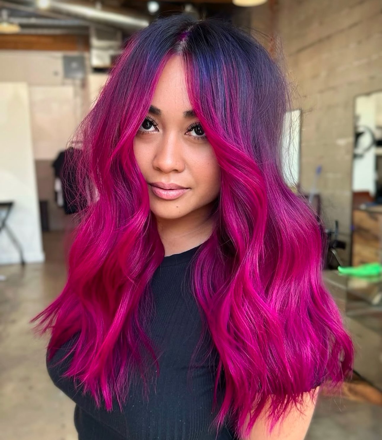 Beautiful woman with vibrant magenta balayage hair color on long wavy hair.